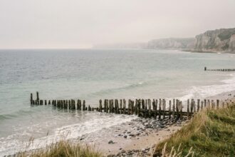 Plage de sable et galets sur la Côte de Nacre en Normandie avec dunes et épis en bois